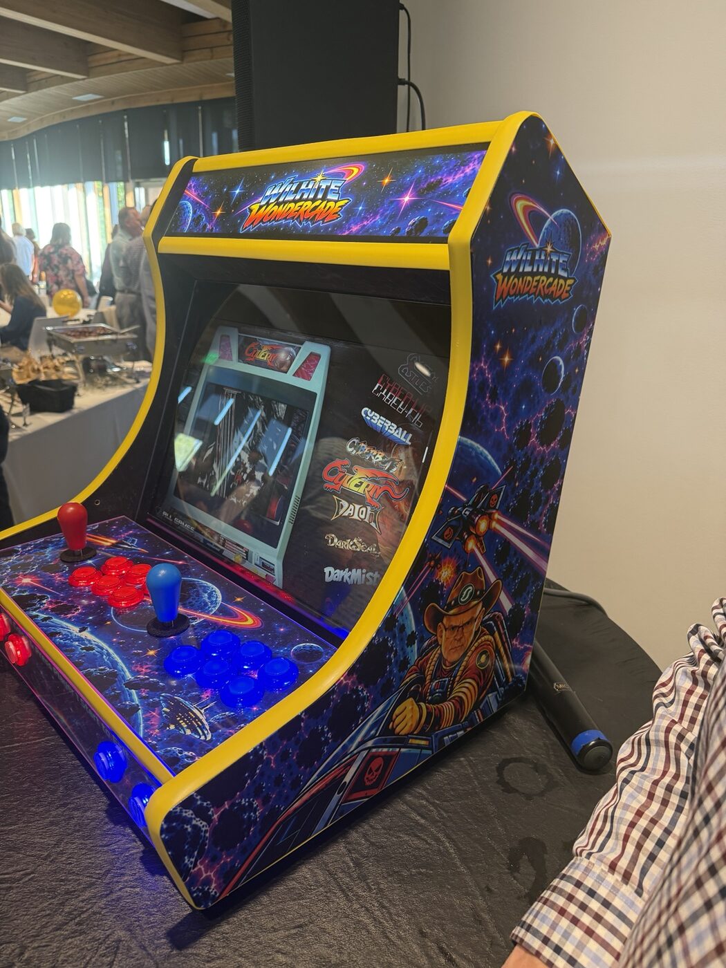 Finished bartop arcade powered on in three-quarter view with yellow trim and framed display