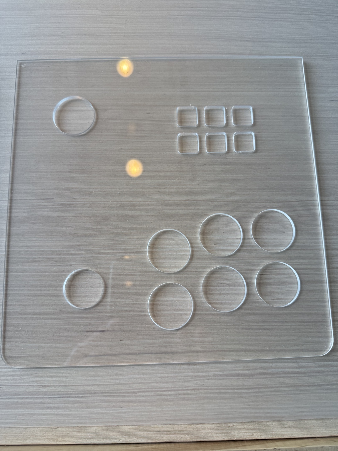 Clear CNC-cut plexiglass alone on the workbench with six separate key apertures and circular control holes