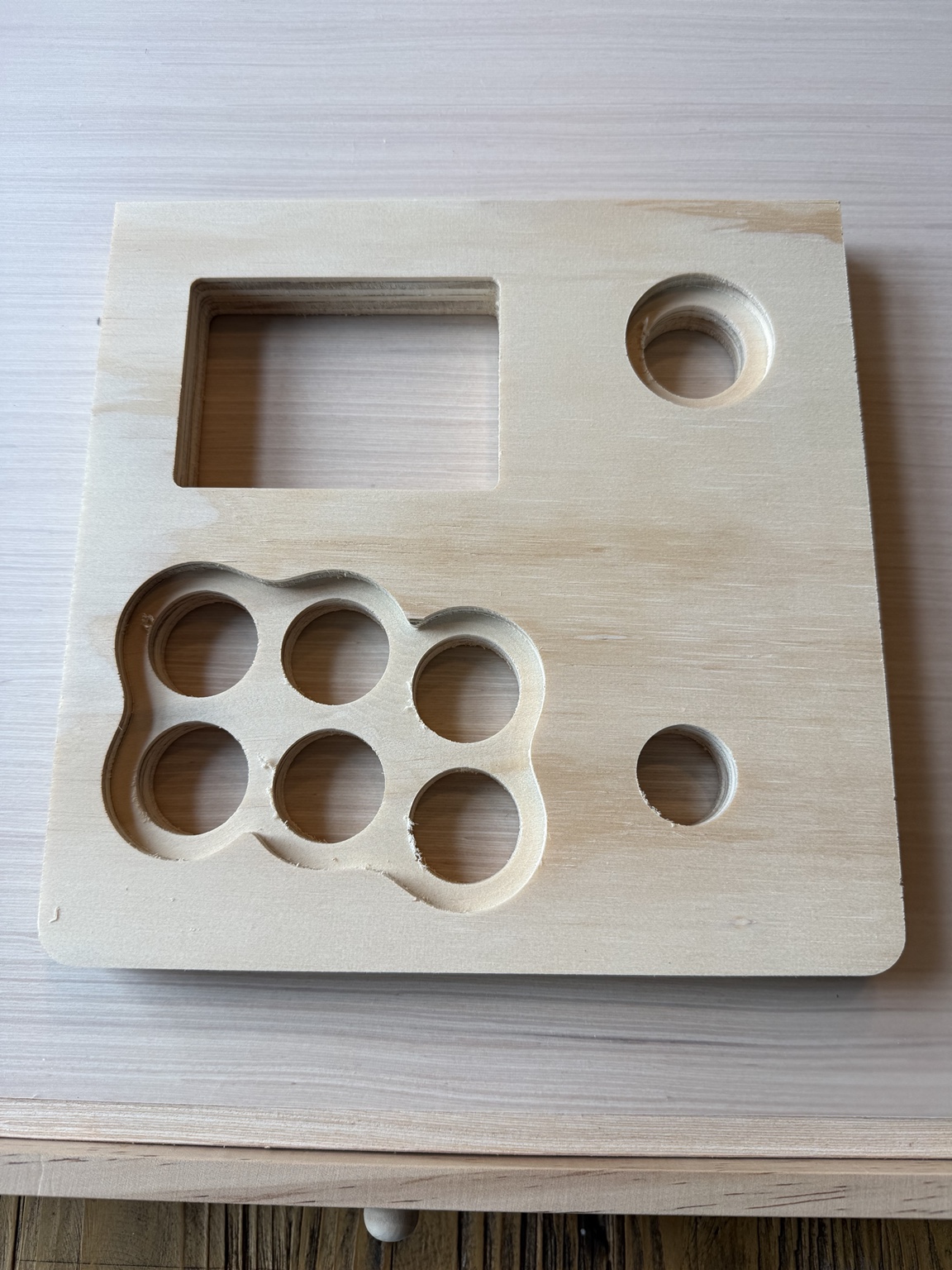 Actual plywood underside with a shared scalloped six-button relief pocket and circular start-button recess